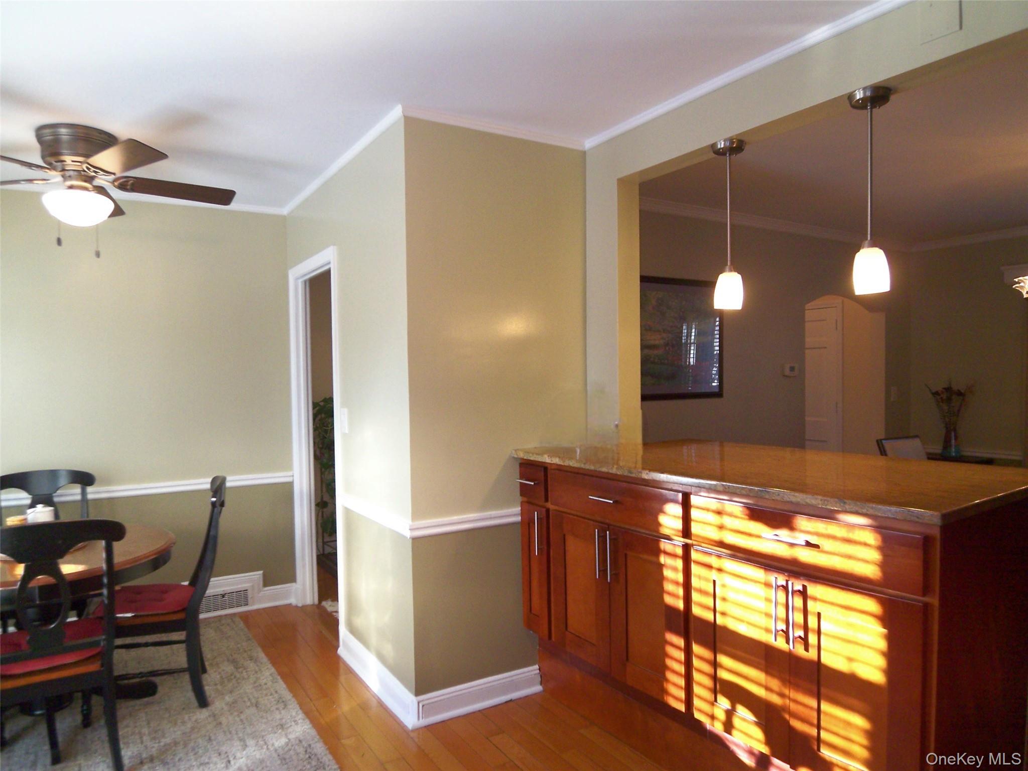 40 Harding Parkway Mount Vernon, NY 10552 - Photo 7 of 35 Bar area with light stone countertops, hanging light fixtures, wood finish cabinetry, a ceiling fan, and light wood-type flooring