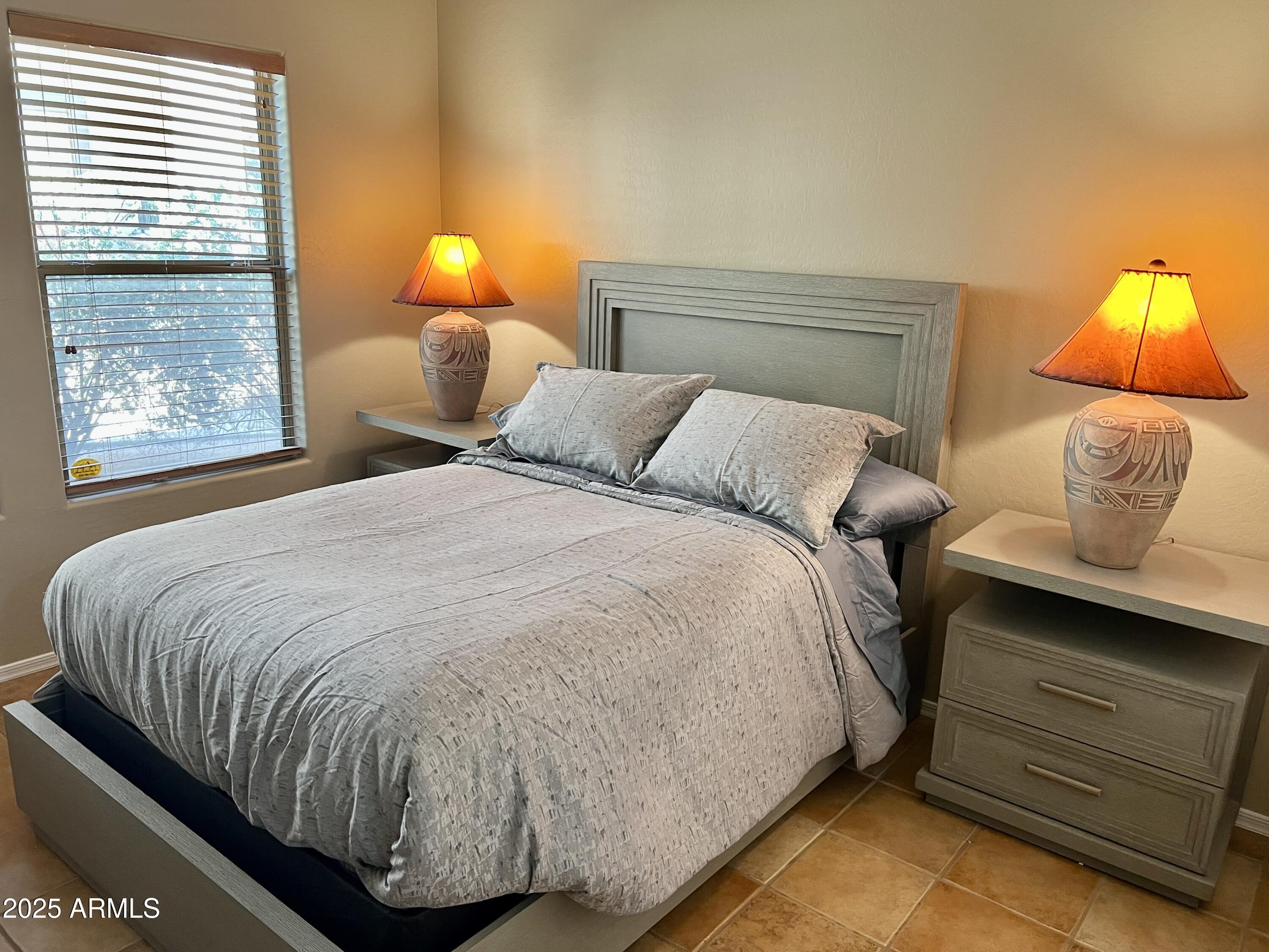 19700 North 76th Street, Unit 1103 Scottsdale, AZ 85255 - Photo 15 of 18 a bed sitting in a bedroom next to a lamp