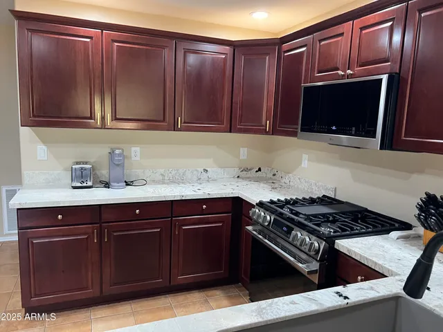 a kitchen with granite countertop stainless steel appliances a sink dishwasher stove and microwave oven