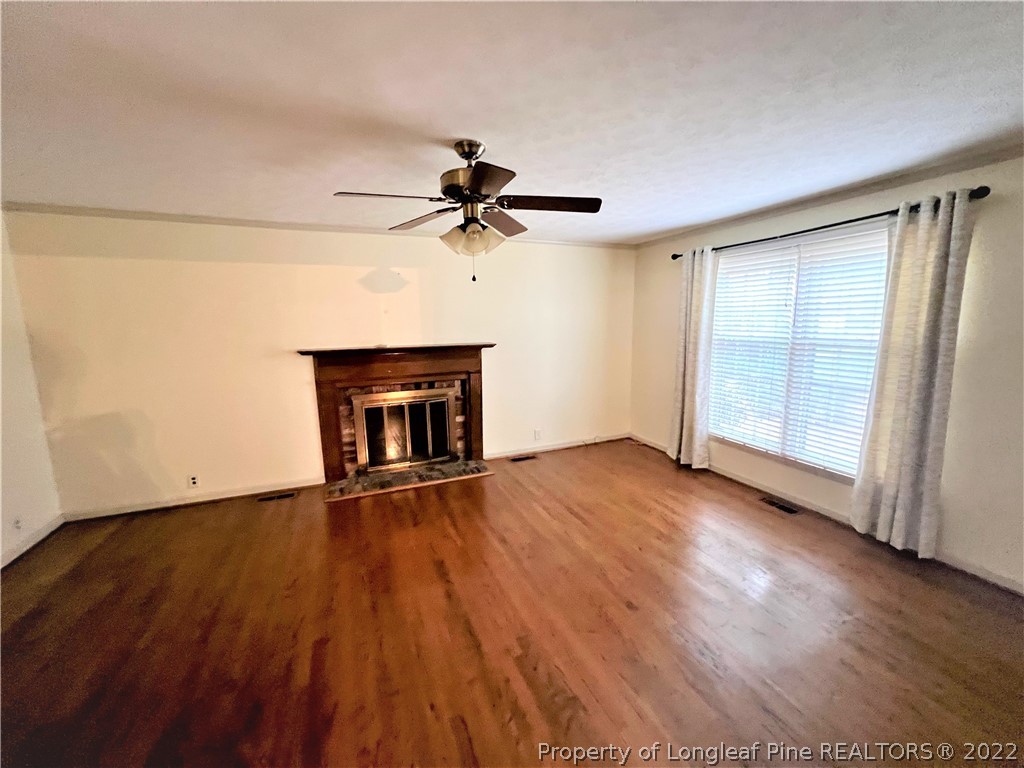 2823 Millbrook Road Fayetteville, NC 28303 - Photo 4 of 20 a view of an empty room with wooden floor fireplace and a window