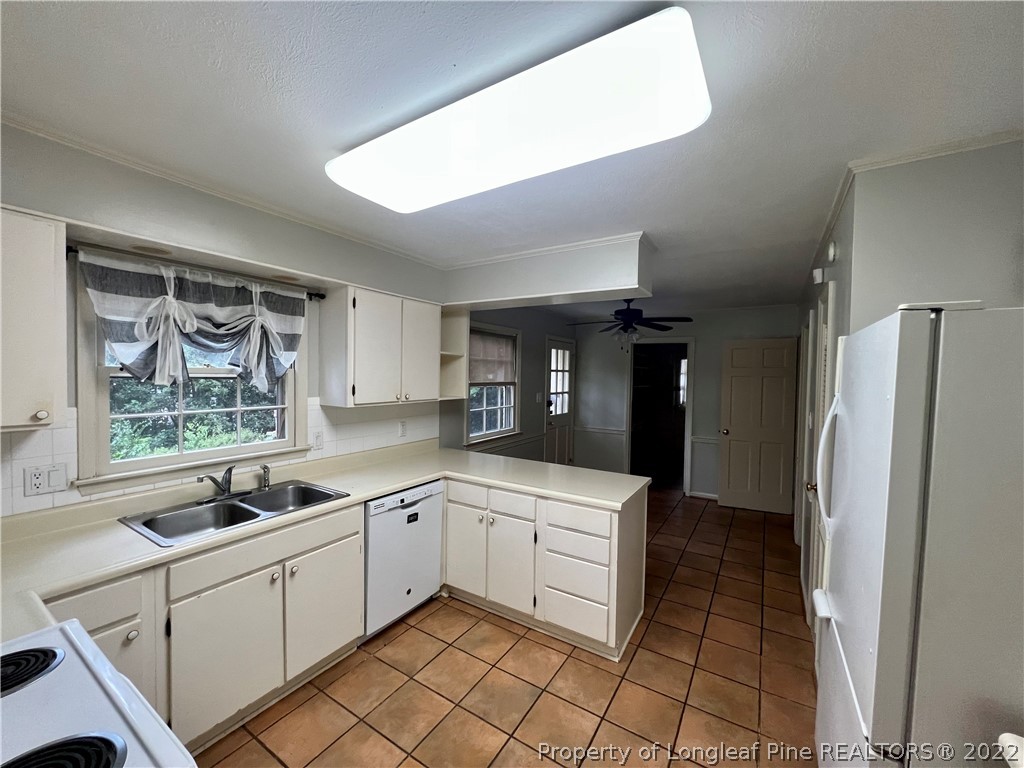 2823 Millbrook Road Fayetteville, NC 28303 - Photo 6 of 20 a kitchen with a sink a refrigerator and cabinets