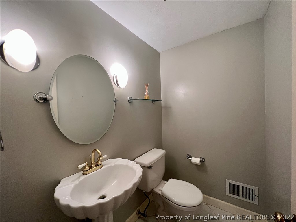 2823 Millbrook Road Fayetteville, NC 28303 - Photo 9 of 20 a bathroom with a toilet a sink and mirror