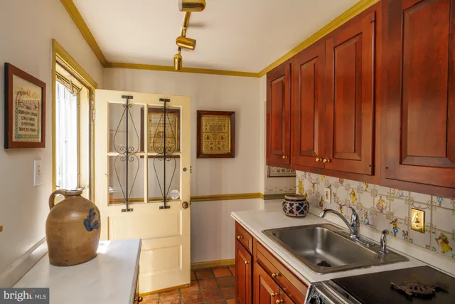 a kitchen that has a sink and a stove with wooden floor