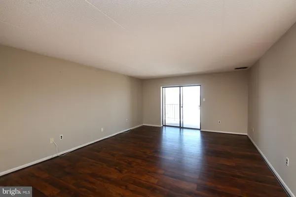 a view of an empty room with wooden floor and window