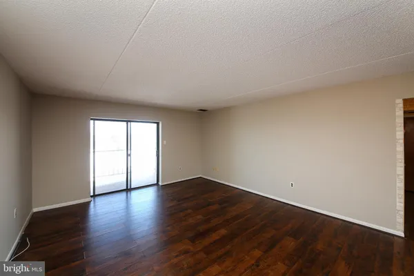 a view of an empty room with wooden floor and window