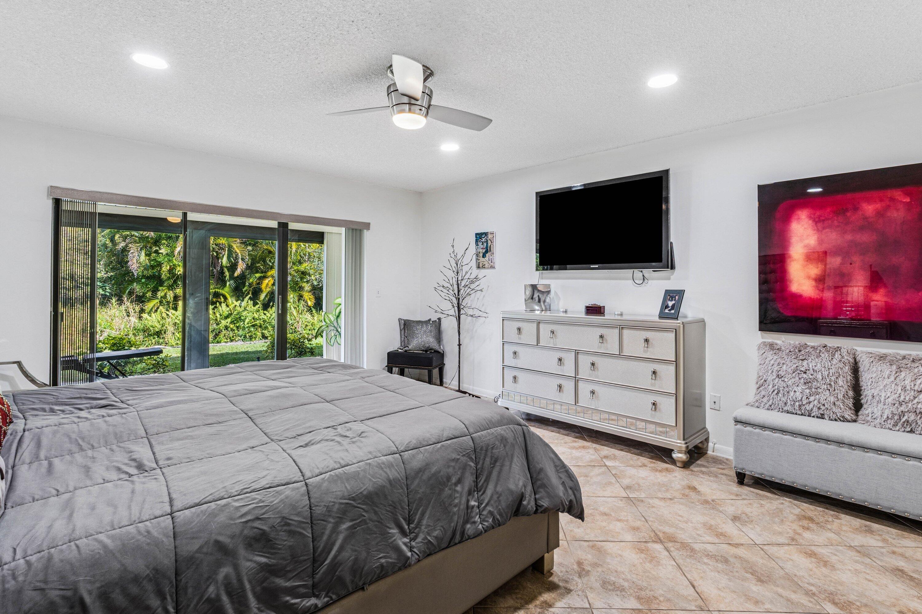 21720 Arriba Real, Unit 37B Boca Raton, FL 33433 - Photo 30 of 41 a spacious bedroom with a bed and a flat screen tv