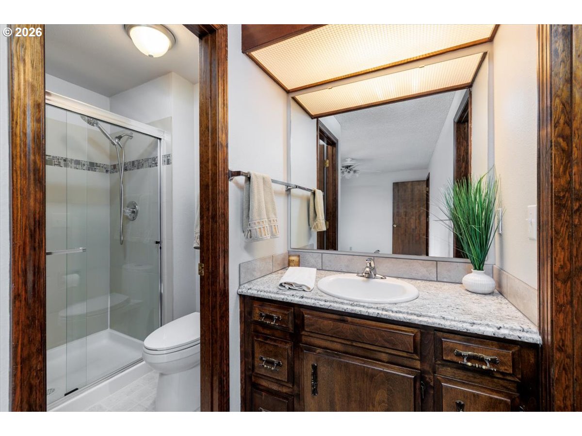 12790 Southwest Cleveland Bay Lane Beaverton, OR 97008 - Photo 17 of 32 a bathroom with a granite countertop sink toilet a mirror a shower and