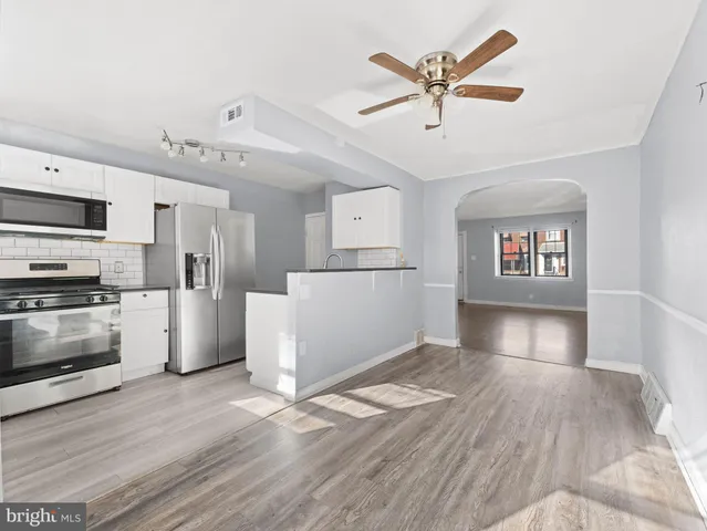 a view of a kitchen with wooden floor and a ceiling fan