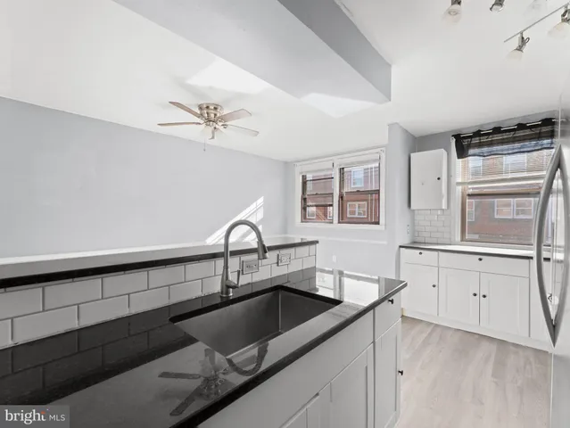 a kitchen with a sink dishwasher a stove and white cabinets with wooden floor