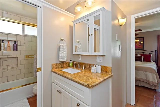a en suite bathroom with a granite countertop sink and a mirror