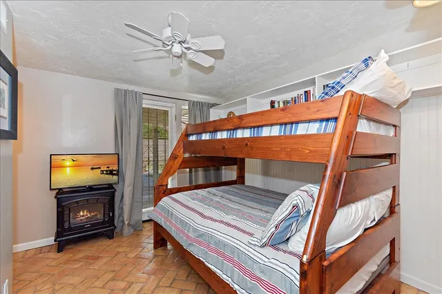 a bedroom with furniture a flat screen tv and a ceiling fan