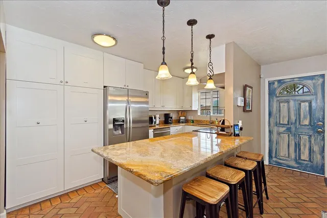 a kitchen with granite countertop a table chairs stove and refrigerator