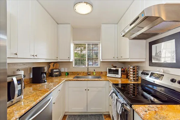 a kitchen with a sink appliances cabinets and a window