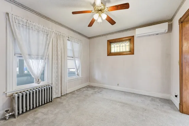 a view of an empty room with window and chandelier fan
