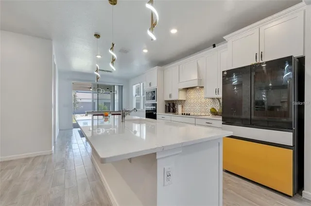 a large kitchen with kitchen island a large counter top space a sink stainless steel appliances and cabinets