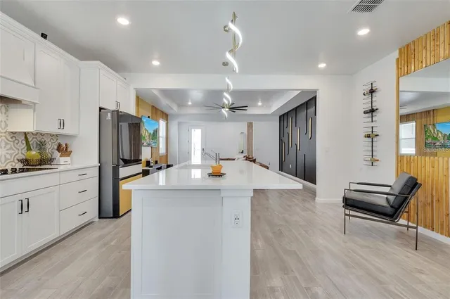 a kitchen with stainless steel appliances kitchen island granite countertop a refrigerator a stove and a sink with wooden floor