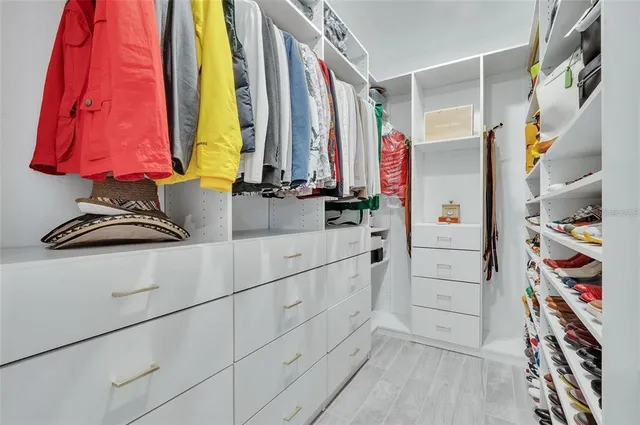 a view of walk in closet with clothes and shoes