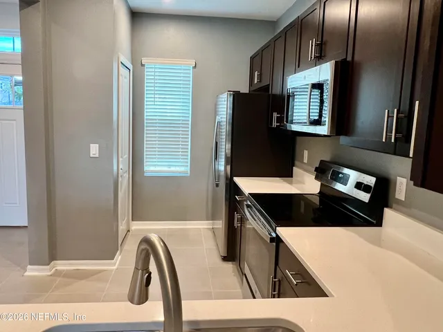a kitchen with granite countertop a stove a sink and a refrigerator