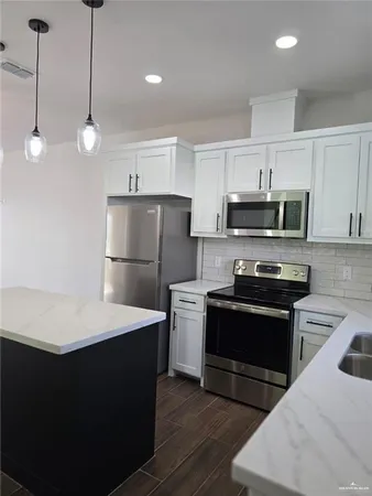 a kitchen with a sink a microwave a refrigerator and white cabinets