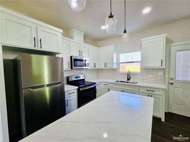 a kitchen with cabinets stainless steel appliances a sink and a window