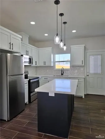 a kitchen with kitchen island granite countertop a sink a counter space stainless steel appliances and cabinets