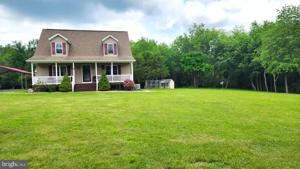 a view of a brick house with a big yard and large trees