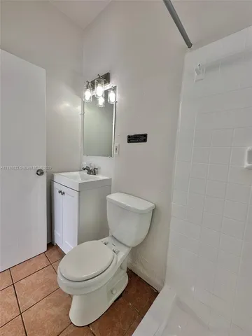 a white toilet sitting next to a bathroom sink and a mirror