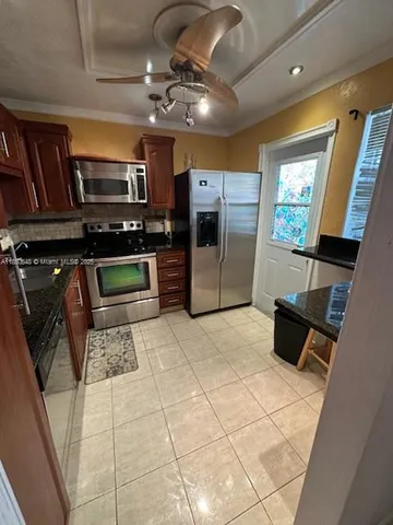 a kitchen with stainless steel appliances kitchen island granite countertop a refrigerator and a stove top oven