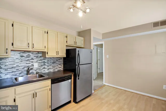 a kitchen with stainless steel appliances granite countertop a refrigerator a sink a stove and white cabinets