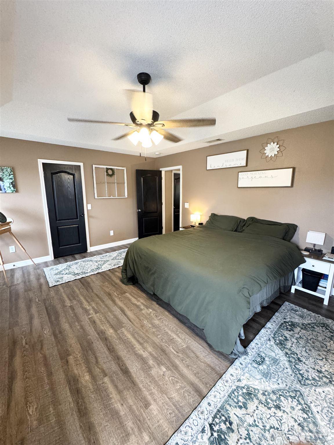 9909 South Trace Road Milton, FL 32583 - Photo 19 of 41 a bedroom with a large bed and a chandelier