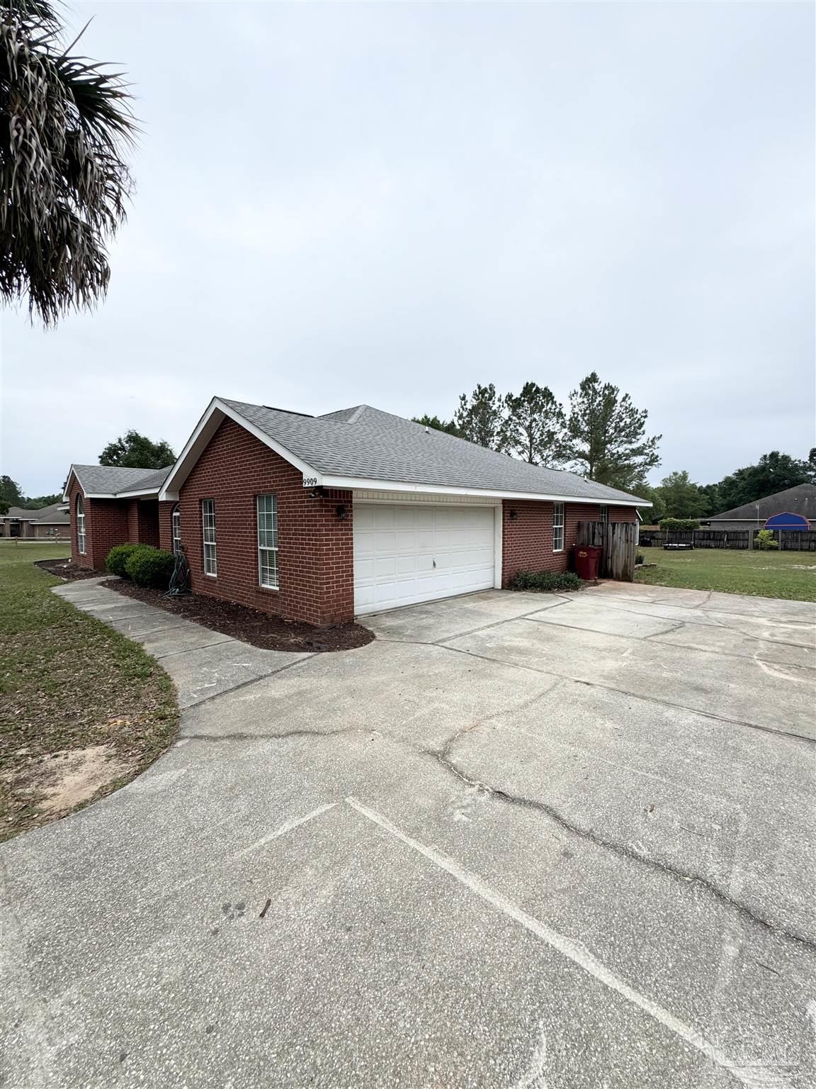 9909 South Trace Road Milton, FL 32583 - Photo 2 of 41 a front view of a house with a yard and garage