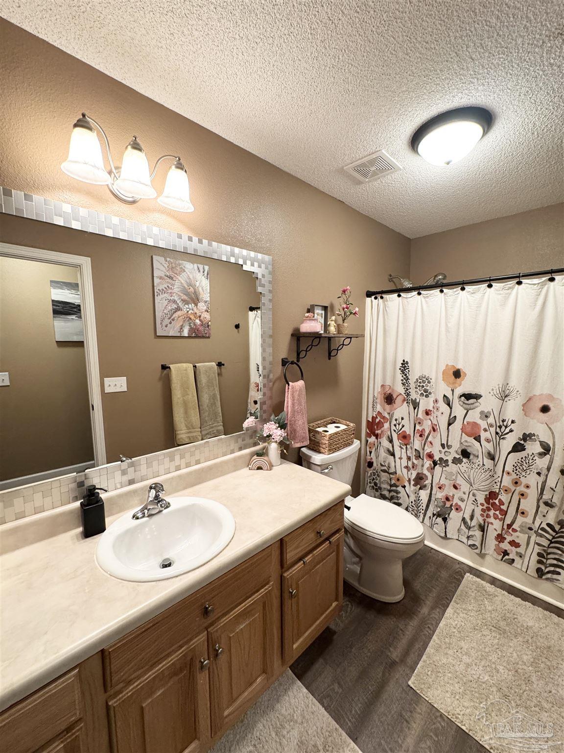 9909 South Trace Road Milton, FL 32583 - Photo 27 of 41 a bathroom with a double vanity sink toilet and a mirror