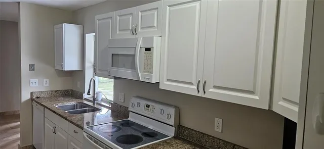 a kitchen with granite countertop a stove a sink and a microwave