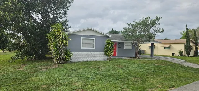 a front view of house with yard and trees in the background