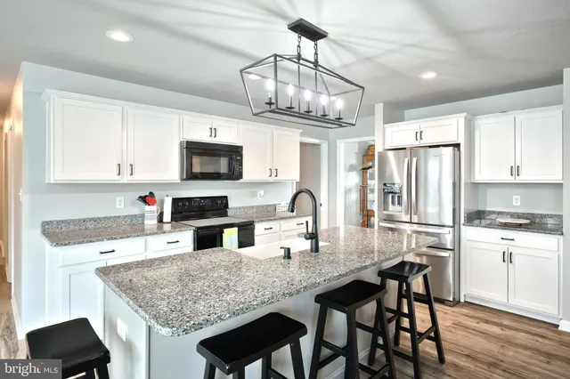 a kitchen with stainless steel appliances granite countertop a kitchen island hardwood floor and a sink