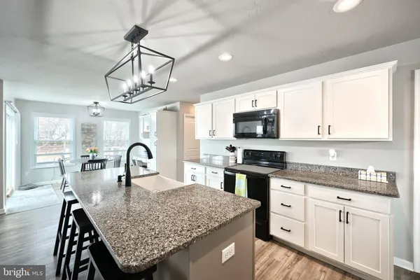 a kitchen with stainless steel appliances granite countertop a stove top oven a sink a dining table and chairs