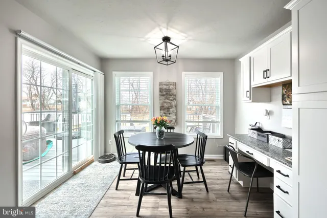 a dining room with wooden floor a chandelier a wooden table and chairs