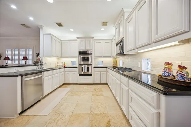a kitchen with granite countertop a sink cabinets and stainless steel appliances