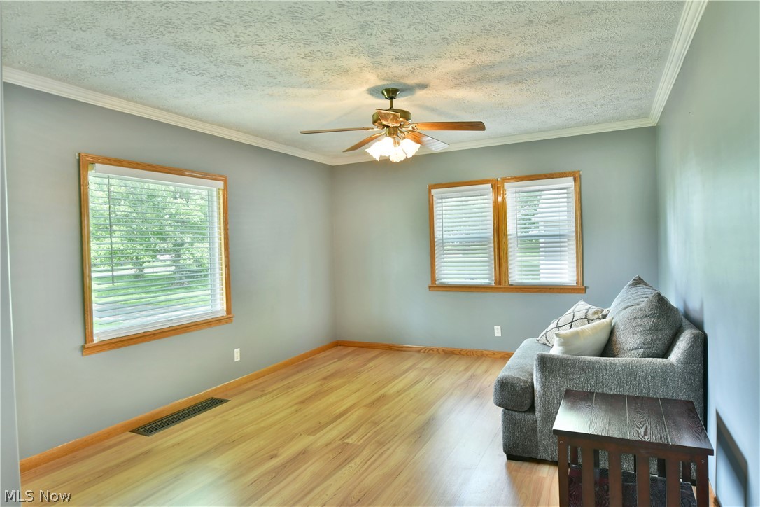 Living area with crown molding, a wealth of natural light, and hardwood / wood-style floors