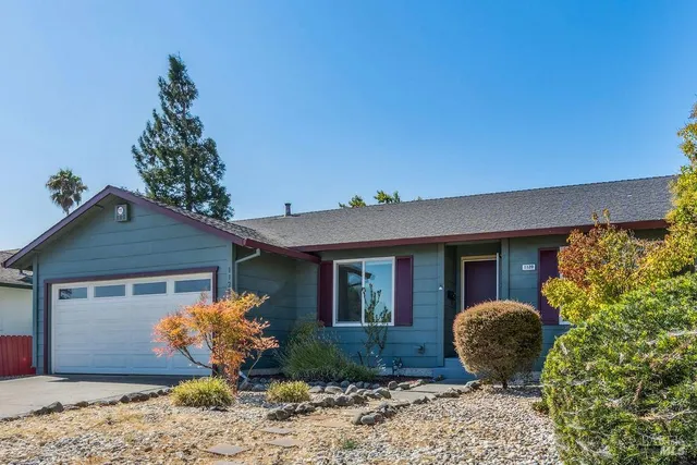a front view of a house with a yard and potted plants