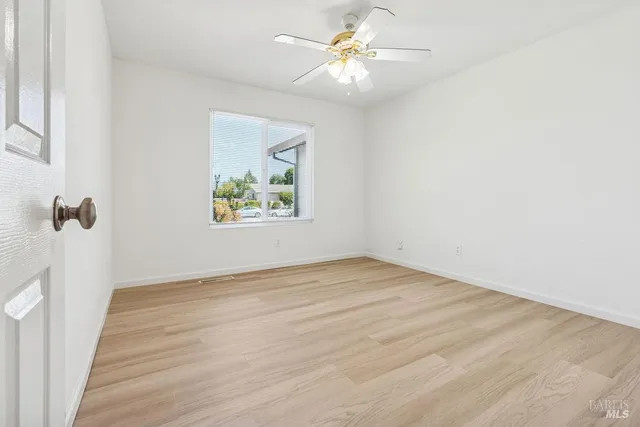 an empty room with wooden floor and fan