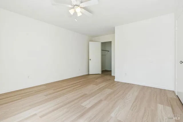 an empty room with wooden floor and fan