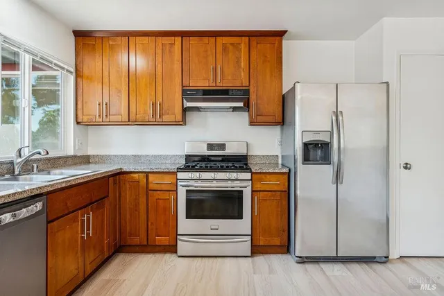 a kitchen with stainless steel appliances granite countertop a stove a refrigerator and a sink