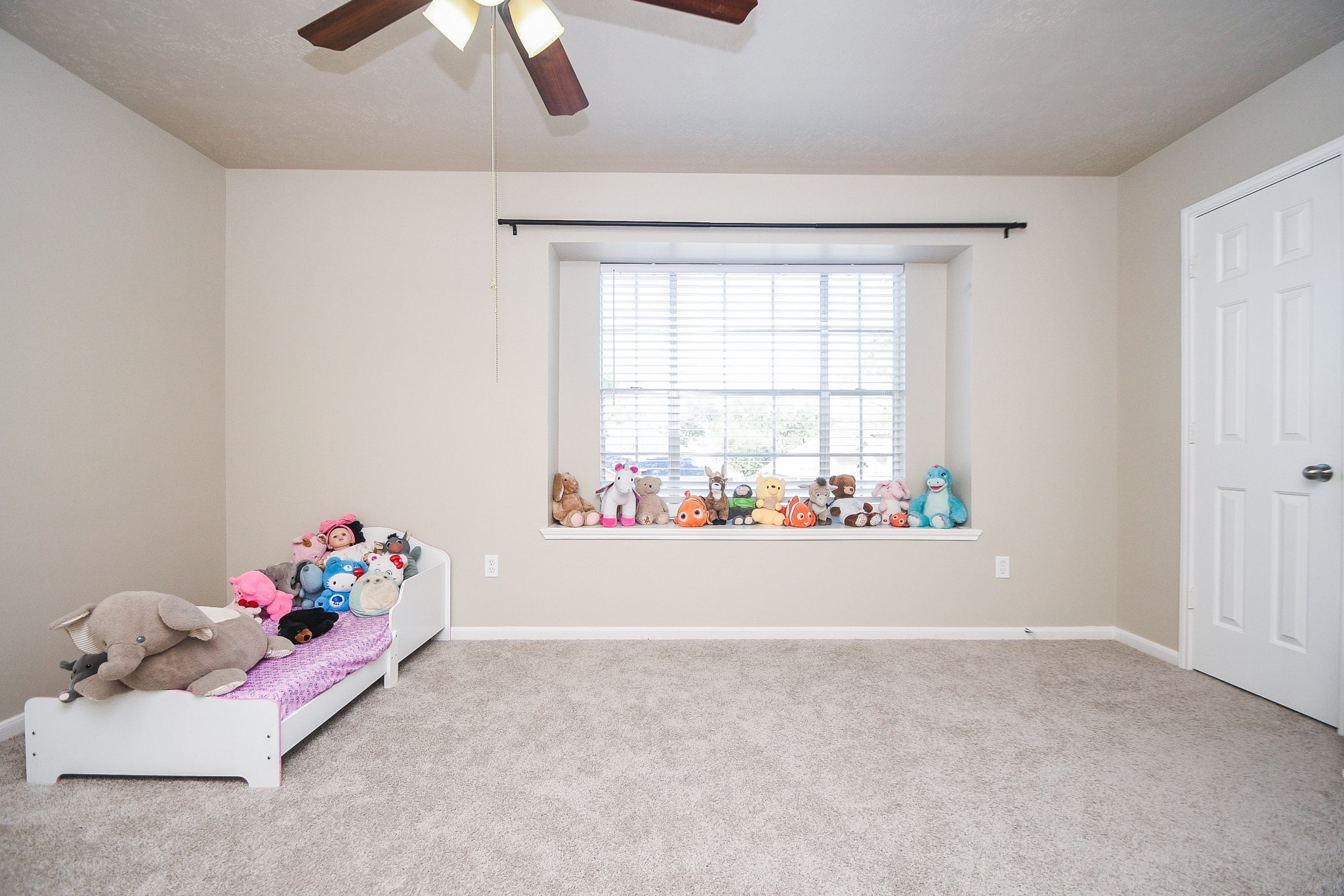 14407 Andrea Way Lane Houston, TX 77083 - Photo 16 of 29 This is a cozy, carpeted bedroom with neutral walls, featuring a window seat with ample natural light. There's a ceiling fan, making it ideal for a child's room.