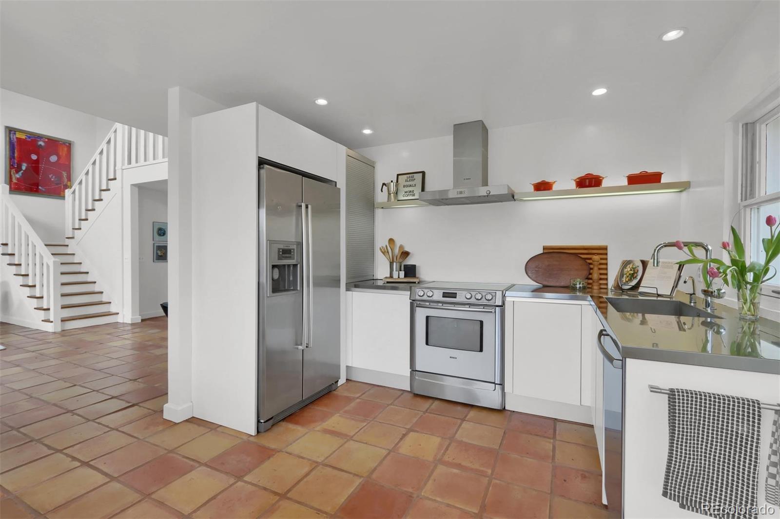 855 Front Range Road Littleton, CO 80120 - Photo 16 of 34 a kitchen with a refrigerator and white cabinets