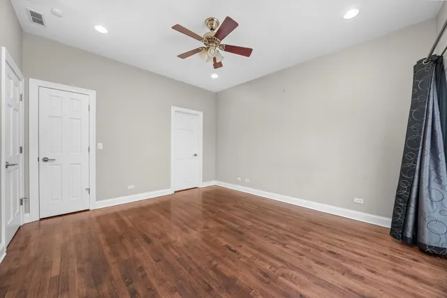 an empty room with wooden floor and a ceiling fan