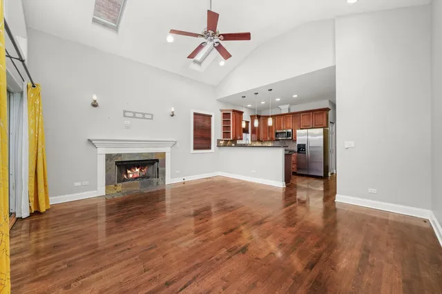 an empty room with wooden floor a fireplace a kitchen view and windows