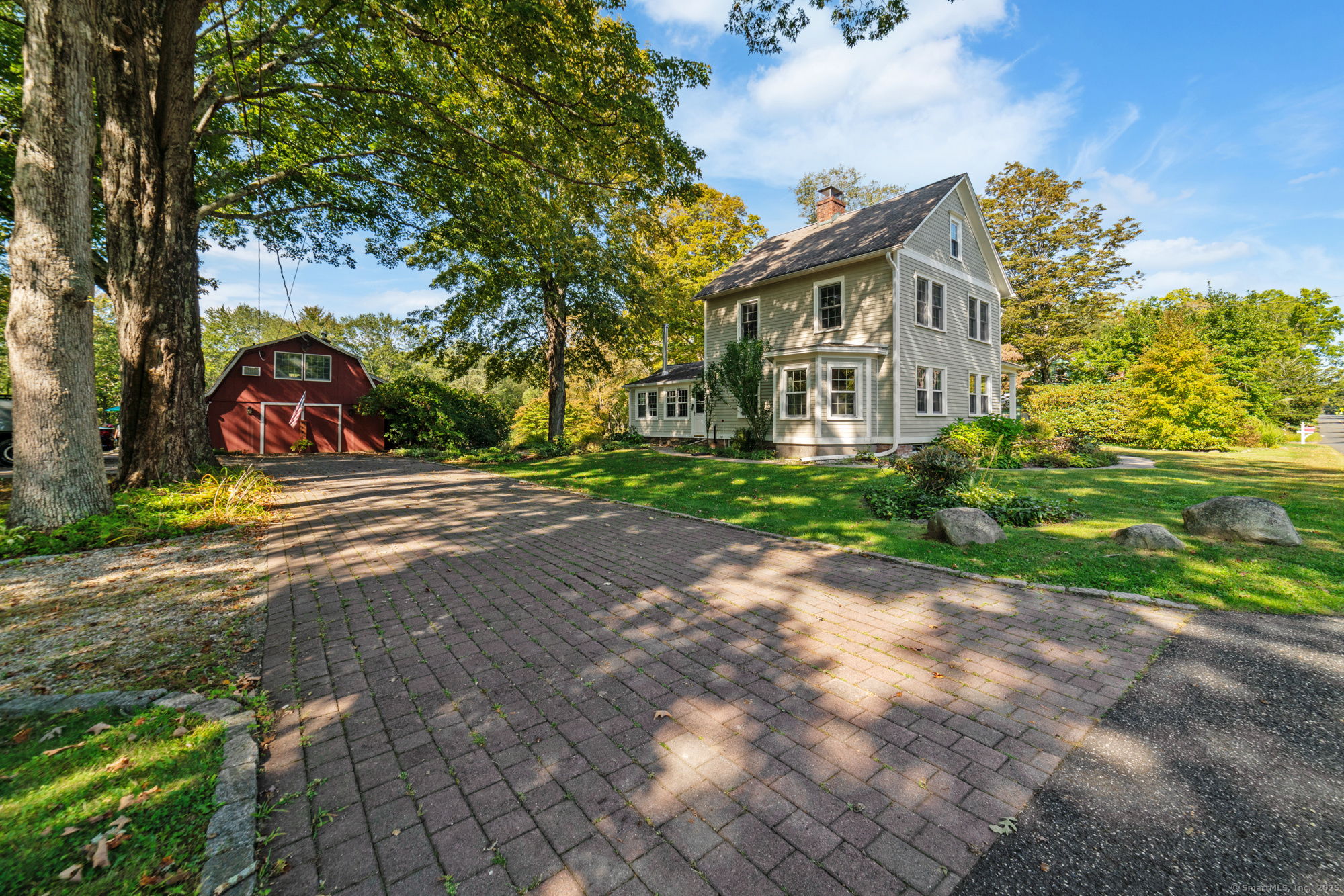 a view of a white house next to a yard with big trees