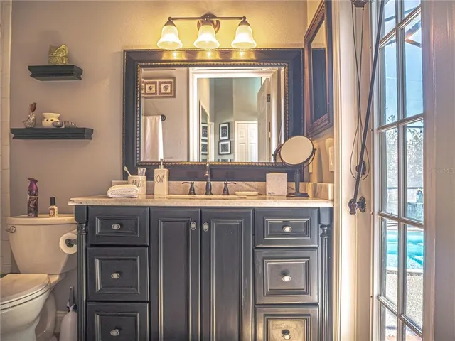 a bathroom with a granite countertop sink a toilet and a mirror