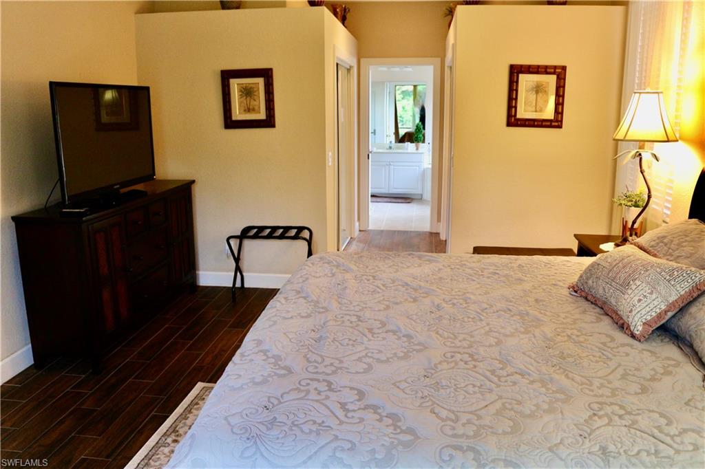 15474 Los Reyes Lane Naples, FL 34110 - Photo 21 of 36 a bedroom with a bed and wooden floor